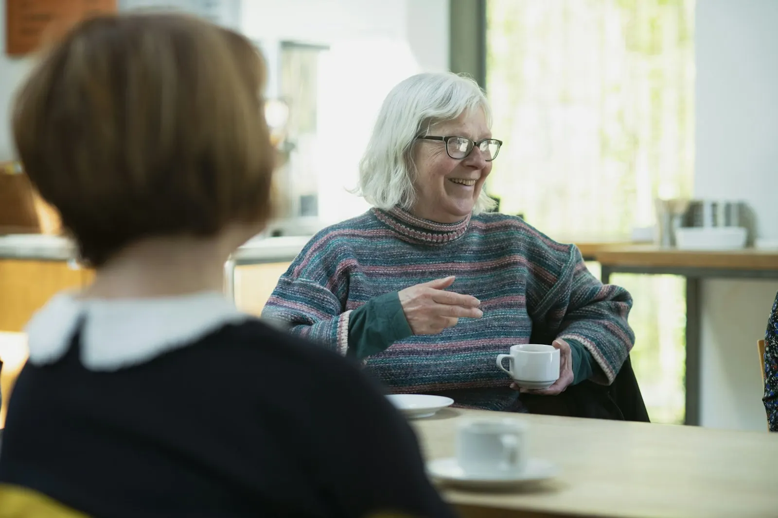 An older woman talking with another woman at a table