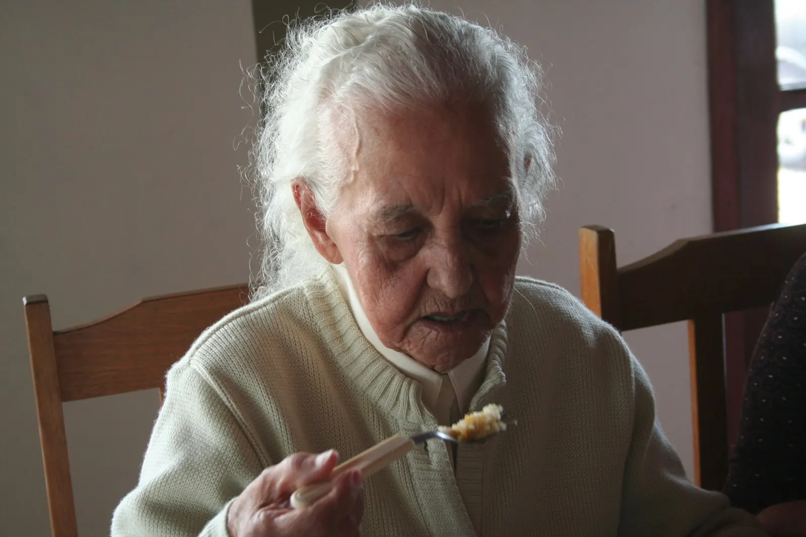 An older woman eating a meal at a table