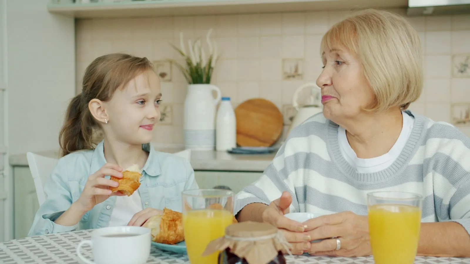 A grandmother and granddaughter having breakfast together at a kitchen table