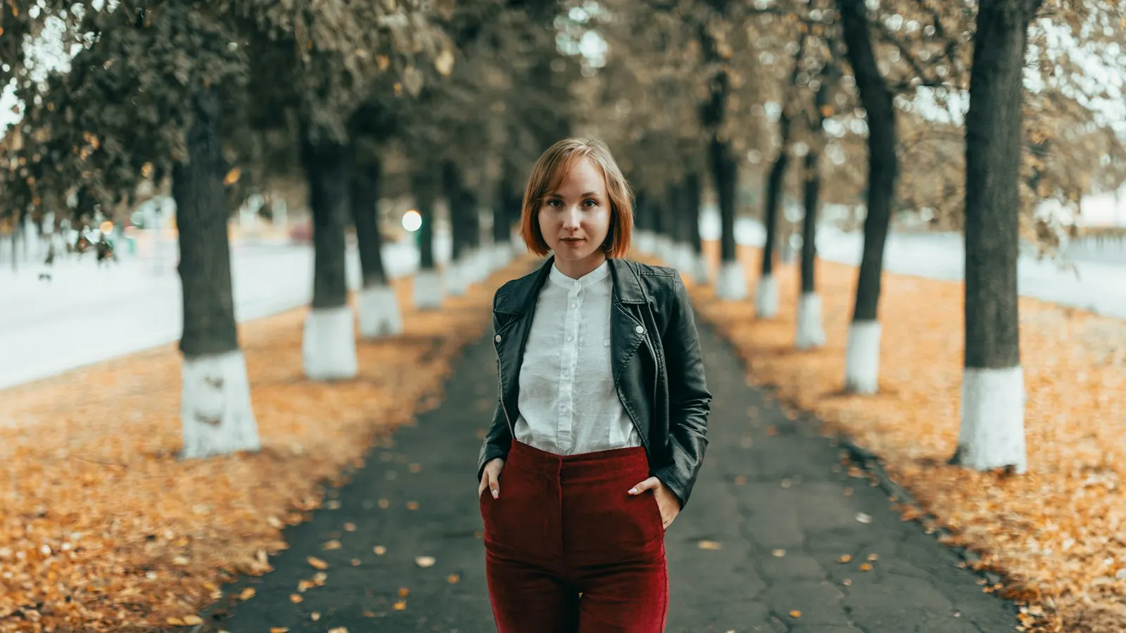 A woman walking along a tree-lined path in autumn