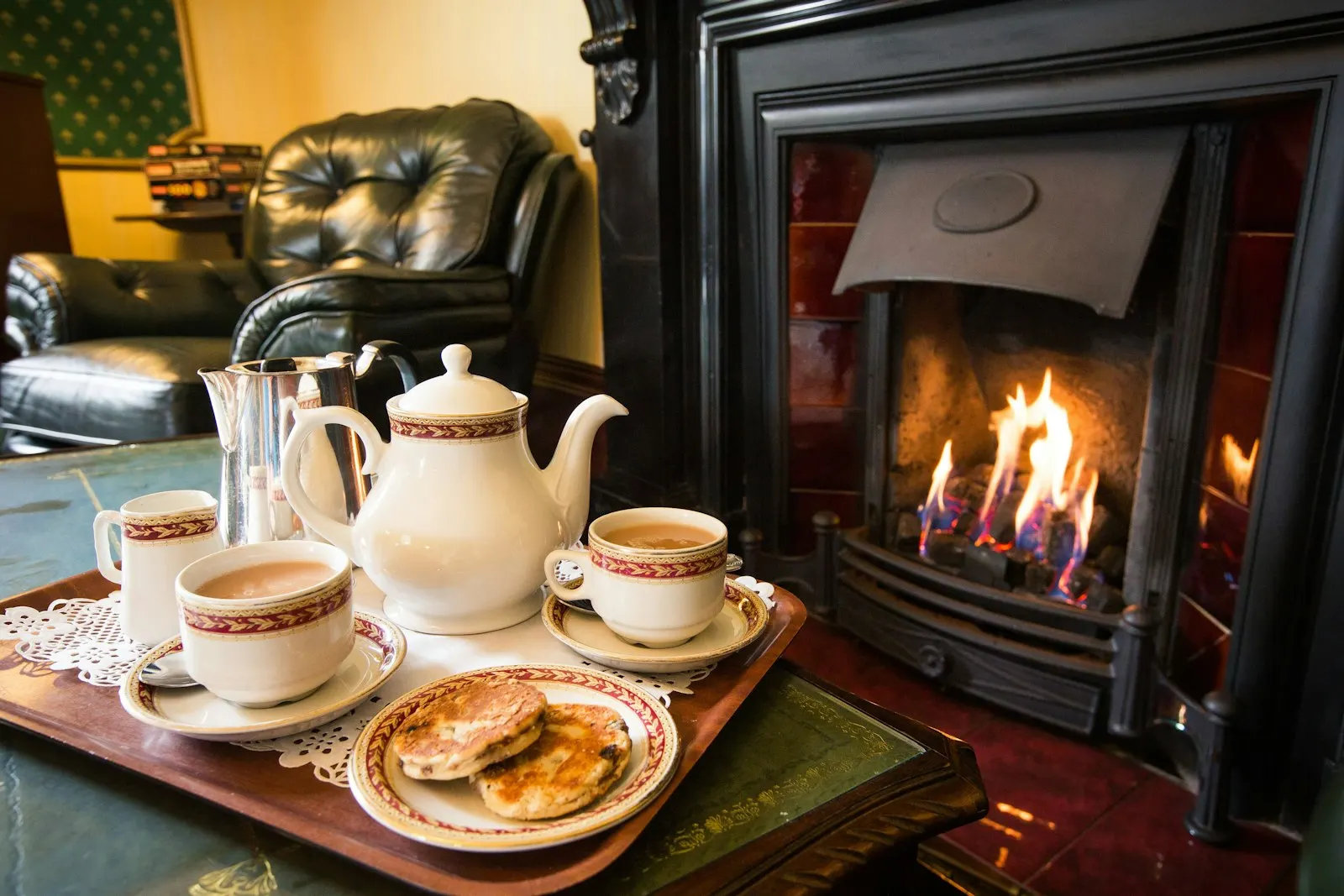 A tray of tea and cakes by an open fire