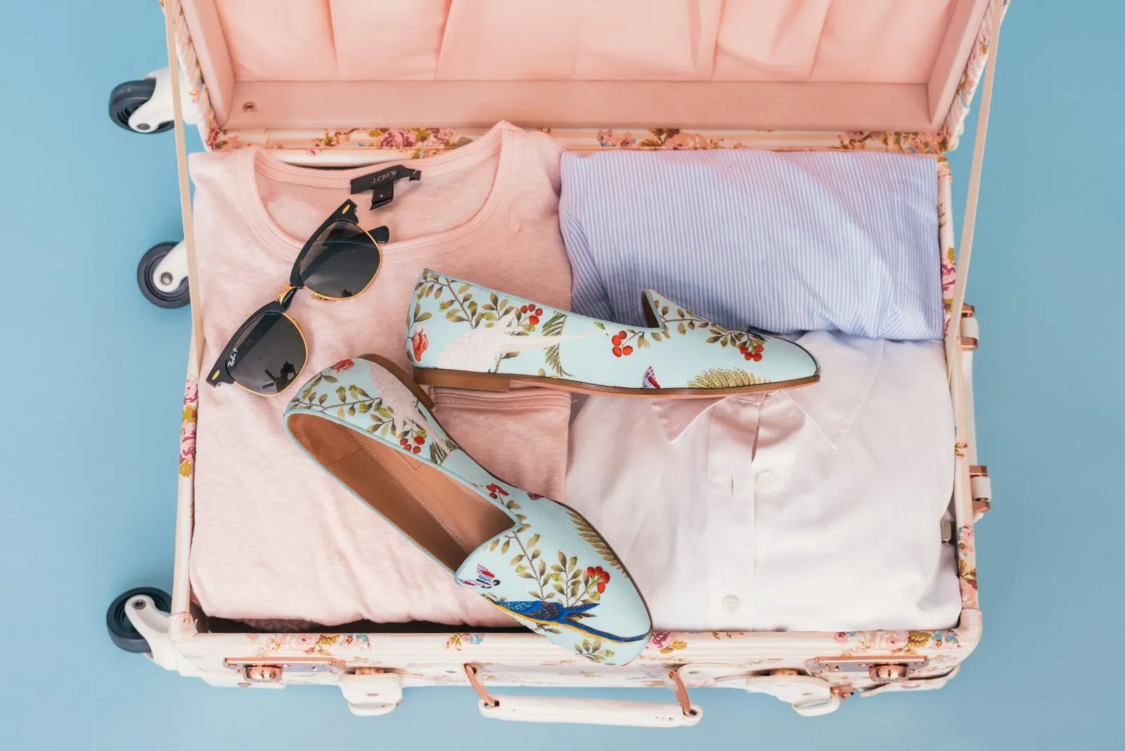 An open suitcase with clothes, shoes and sunglasses