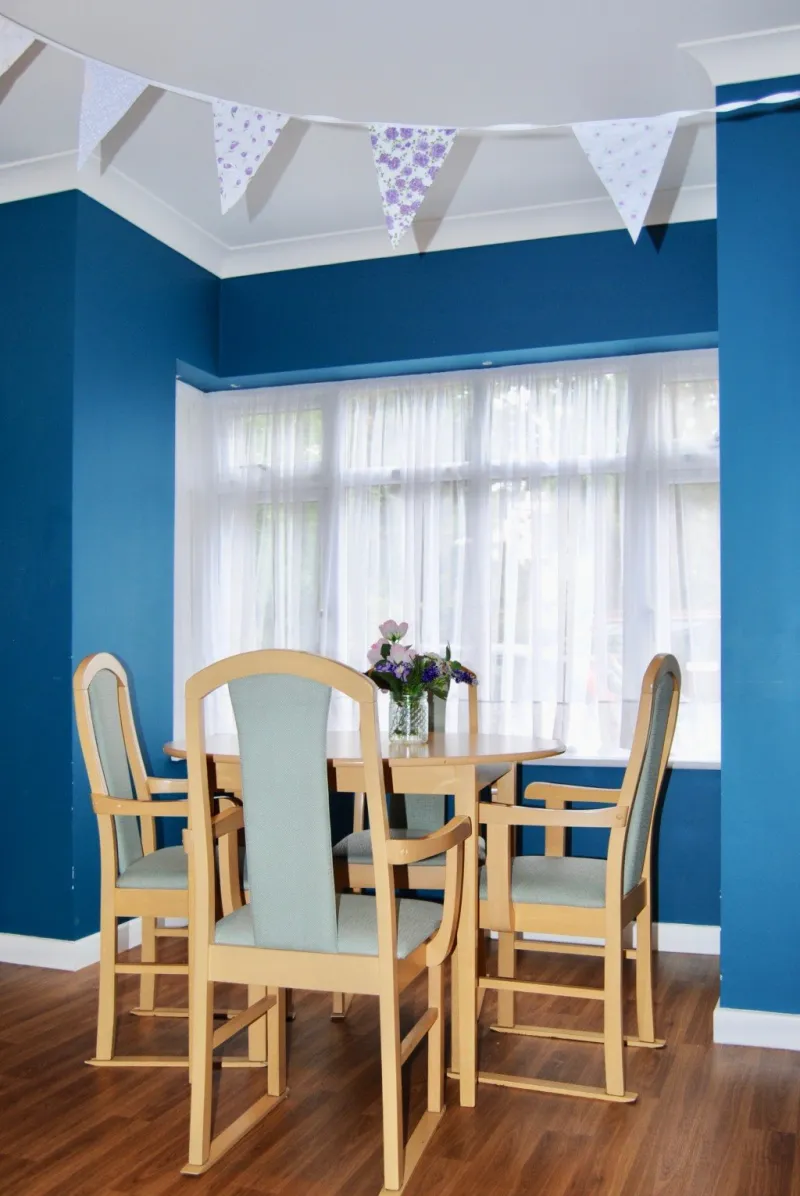 A table for four in a bay window with a blue feature wall and bunting