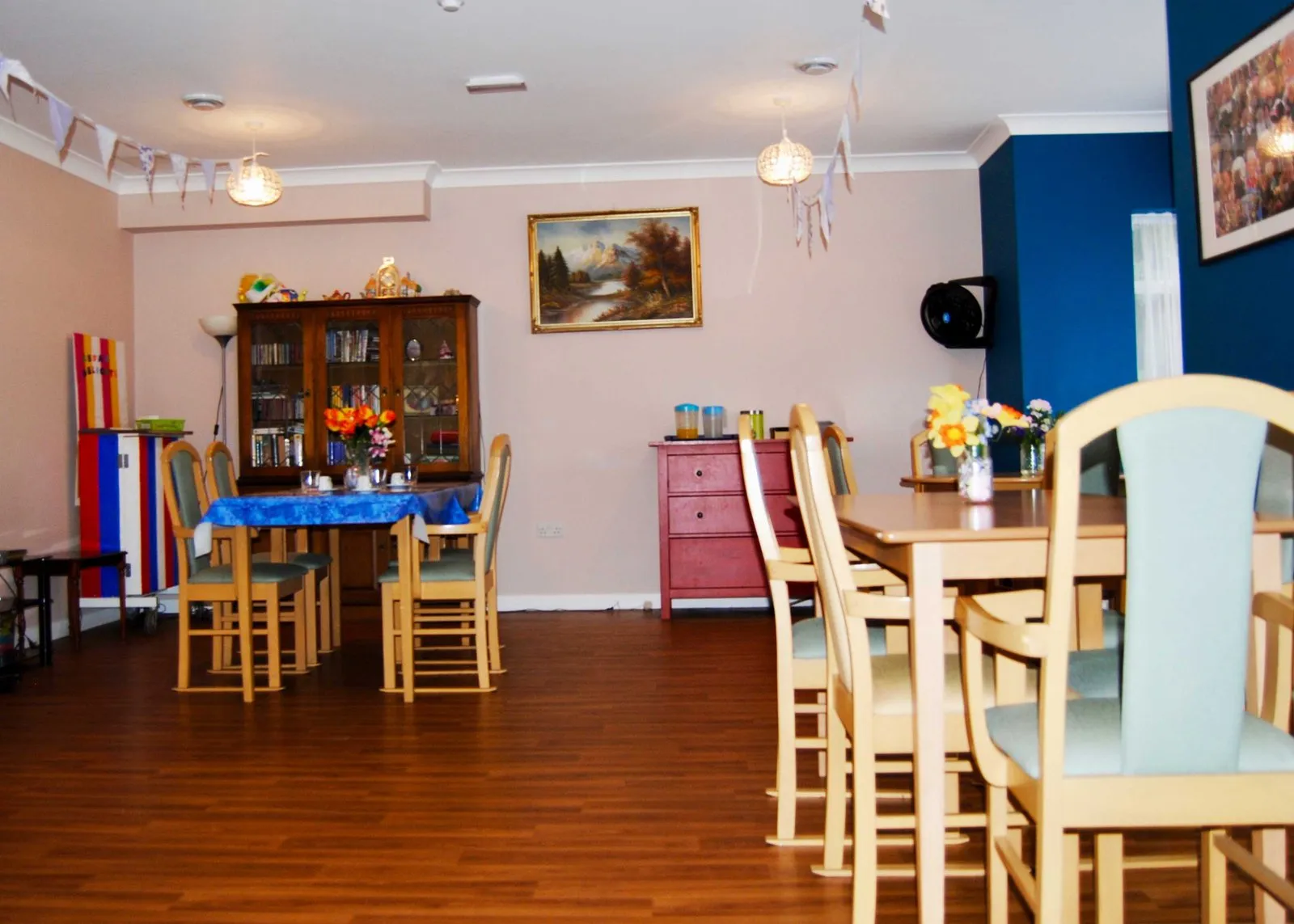 The dining room: wooden tables and chairs, a dresser and a blue feature wall