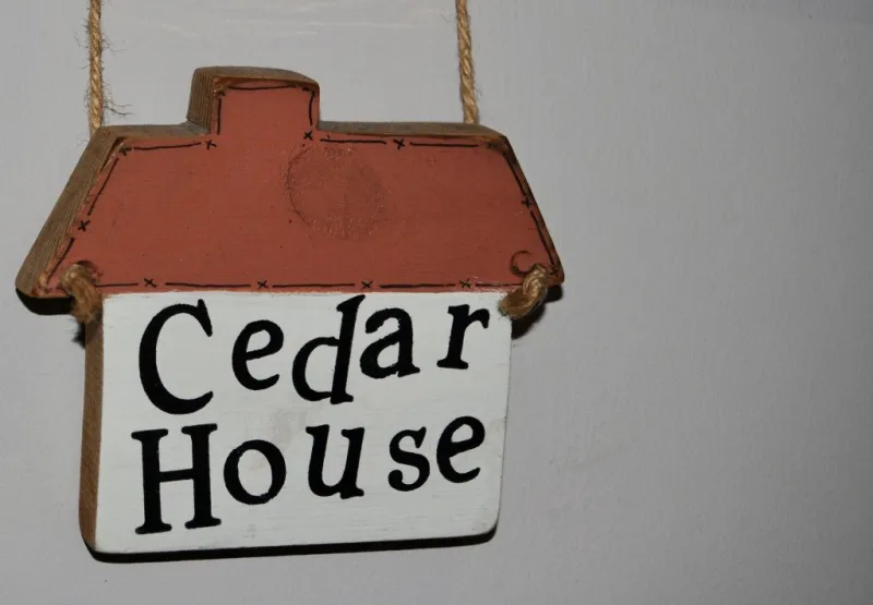 A small house-shaped wooden sign reading Cedar House