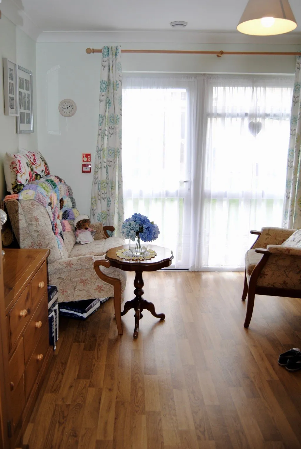 A bright lounge with patio doors, a patchwork throw on the sofa and a small round table