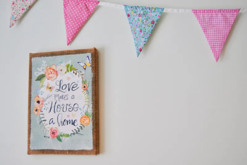A framed sign reading Love makes a house a home below bunting