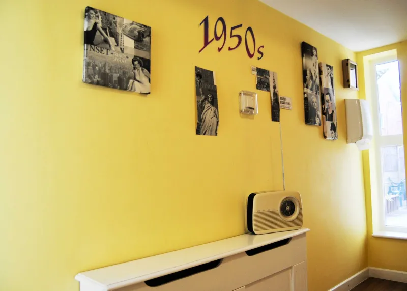 A yellow wall titled 1950s with black and white photos and a vintage radio