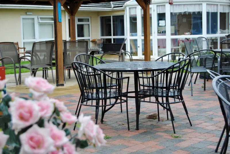 Patio tables and chairs under the pagoda, looking towards the bedroom windows