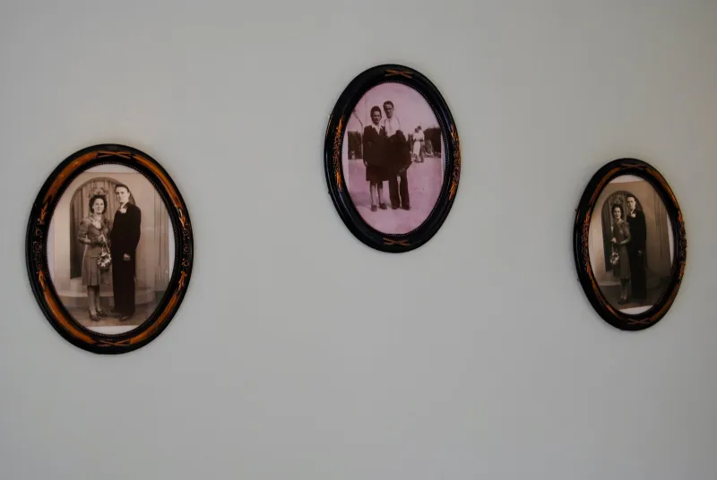 Three old family portraits in oval frames on a bedroom wall