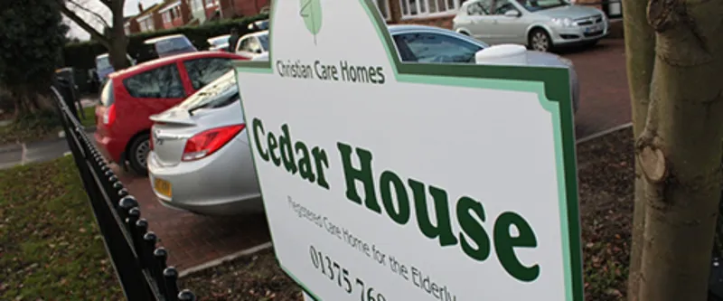 The Cedar House sign by the road: Registered Care Home for the Elderly, 01375 768 505
