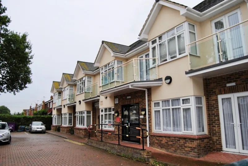 Cedar House seen along its front, with balconies on the first floor and the main entrance below